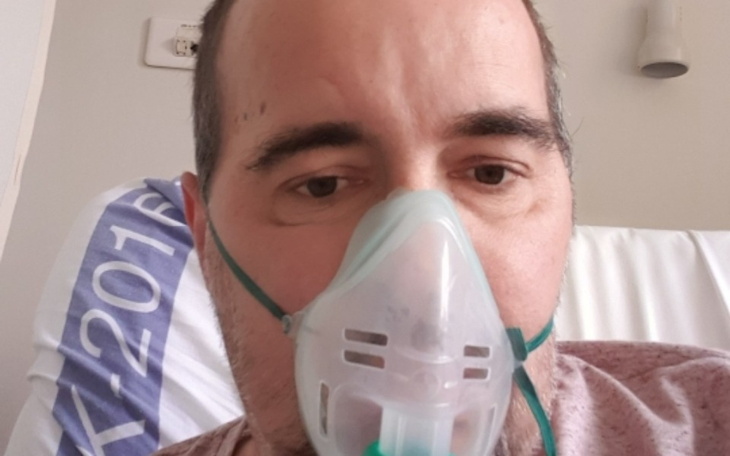 Mężczyzna w szpitalu z maską tlenową na twarzy.