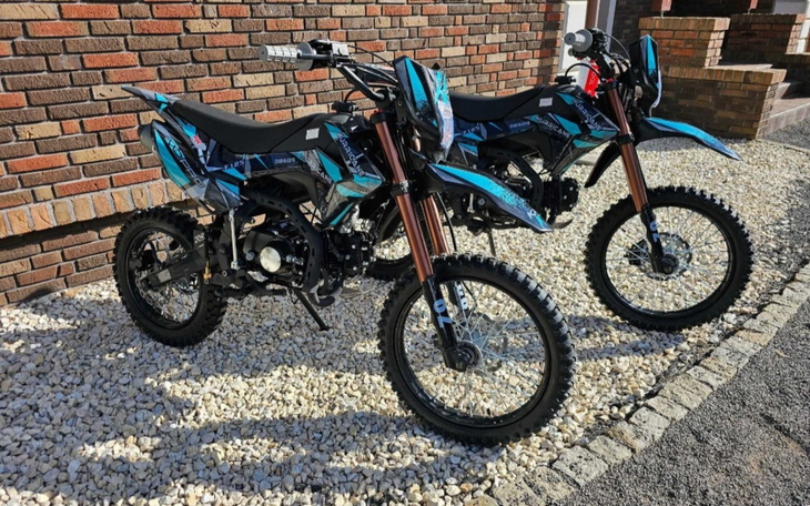 Dwa motocykle terenowe zaparkowane na podjeździe.