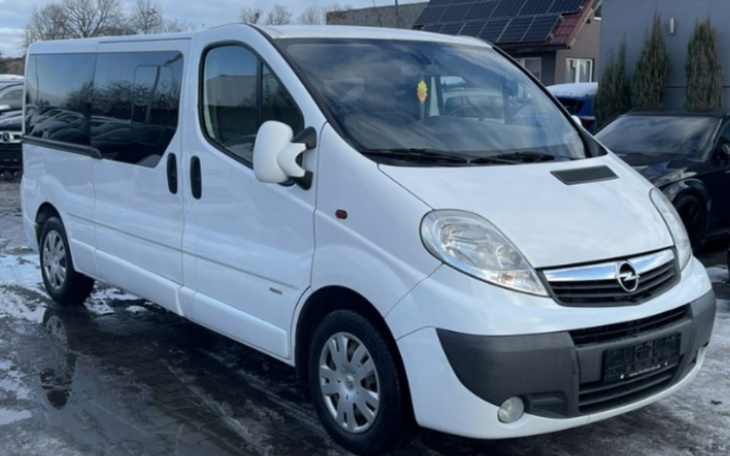 Biały van zaparkowany na podjeździe, w tle widać domy.