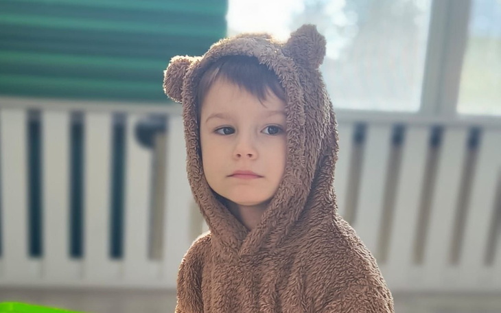 Chłopiec w misiowym kapturze, patrzy w zamyśleniu.