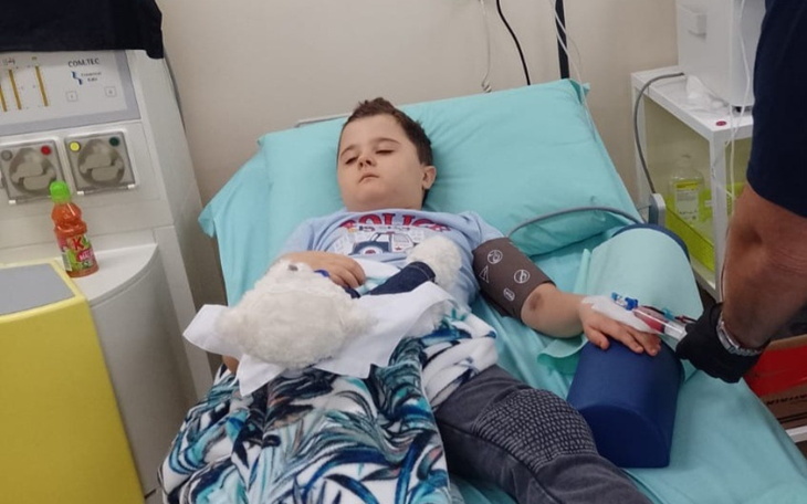 Chłopiec w szpitalu z maskotką, leżący na łóżku szpitalnym.