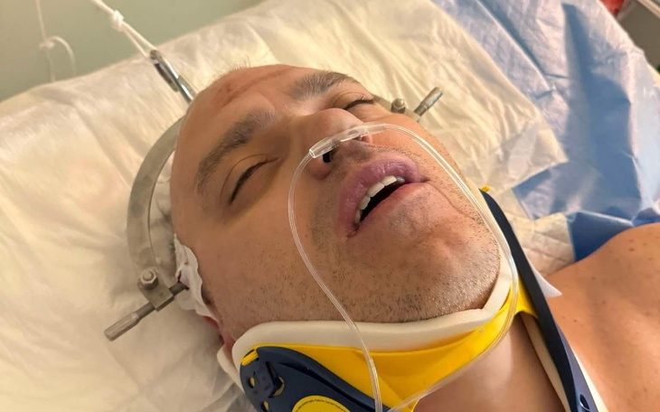Mężczyzna w szpitalu, z rurkami tlenowymi i unieruchomioną szyją.