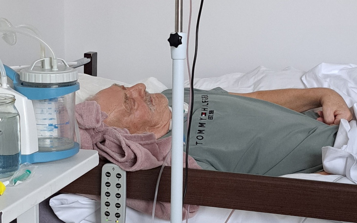 Starszy mężczyzna leżący w szpitalnym łóżku, z ręcznikiem na głowie.