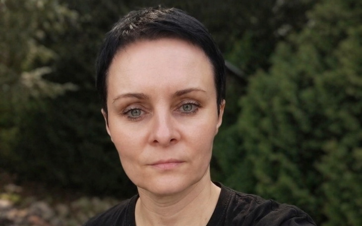 Kobieta z krótkimi włosami patrzy w obiektyw.