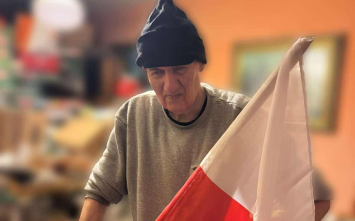 Mężczyzna trzymający flagę Polski, ubrany w czapkę.