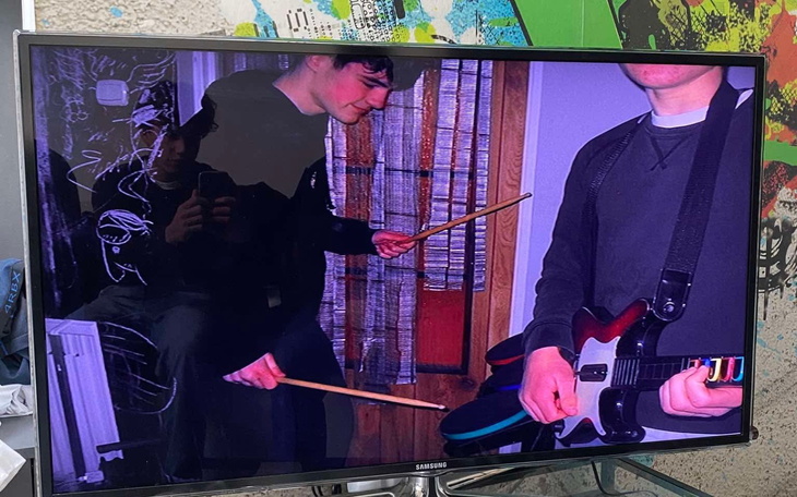 Dwóch młodych ludzi gra na instrumentach w domowym otoczeniu.