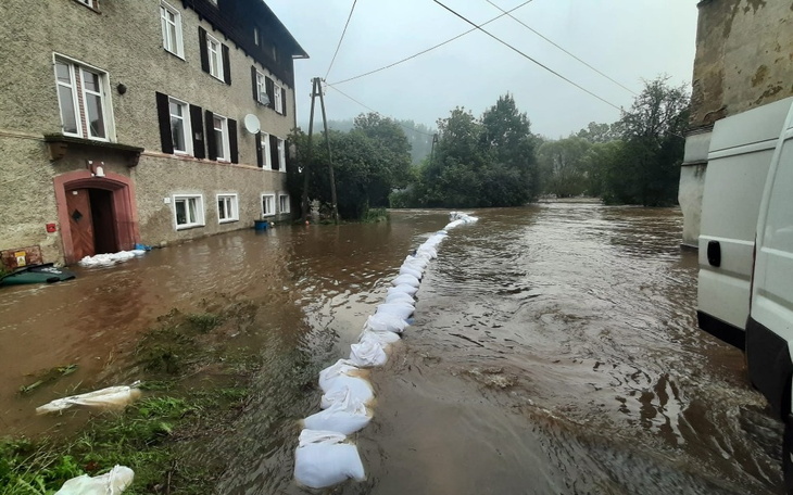 Zalane ulice z workami na piasek wzdłuż budynku.