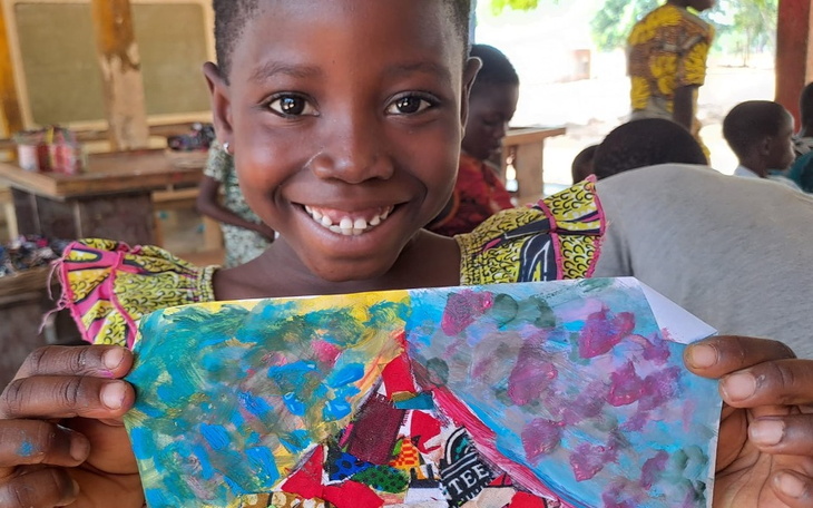 Uśmiechnięta dziewczynka trzymająca swoje dzieło sztuki.