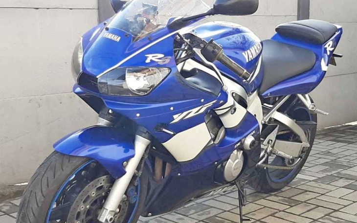 Niebieski motocykl sportowy na tle szarej ściany.