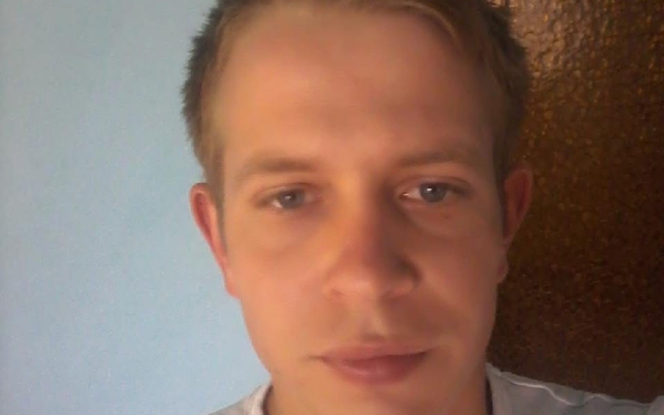 Mężczyzna z neutralnym wyrazem twarzy, patrzy w obiektyw.