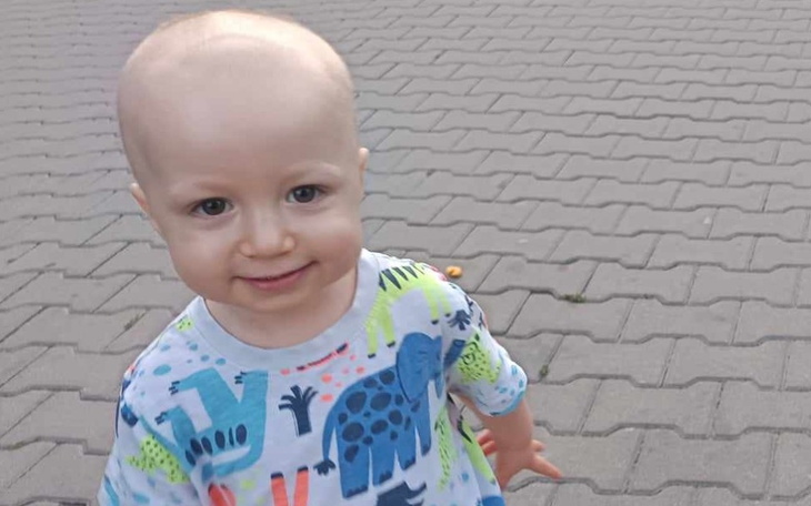 Uśmiechnięty mały chłopiec bawiący się na chodniku.