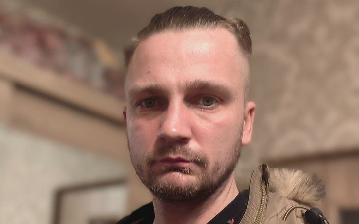 Mężczyzna z krótkimi włosami, patrzący w kamerę.