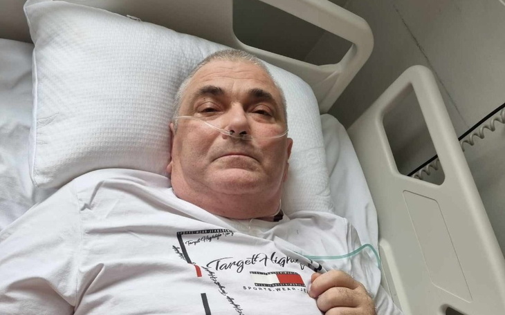 Mężczyzna leżący w szpitalnym łóżku, z tlenem na twarzy.