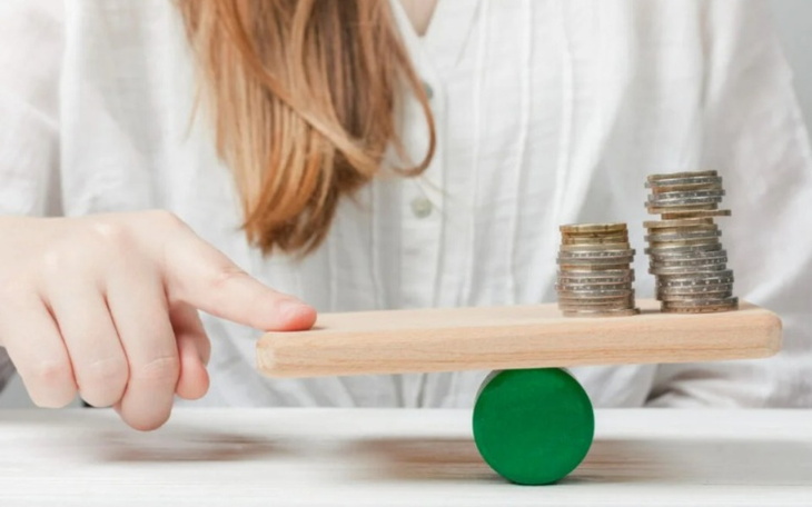 Osoba balansująca monety na desce, symbolizująca oszczędzanie.