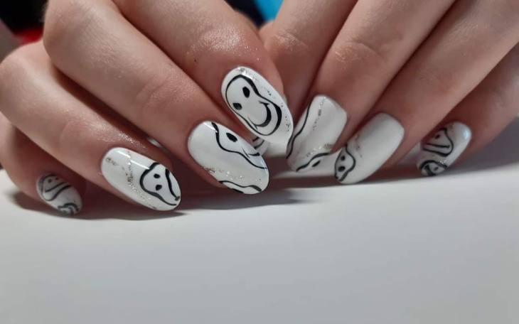 Ręce z paznokciami ozdobionymi uśmiechniętymi buźkami.