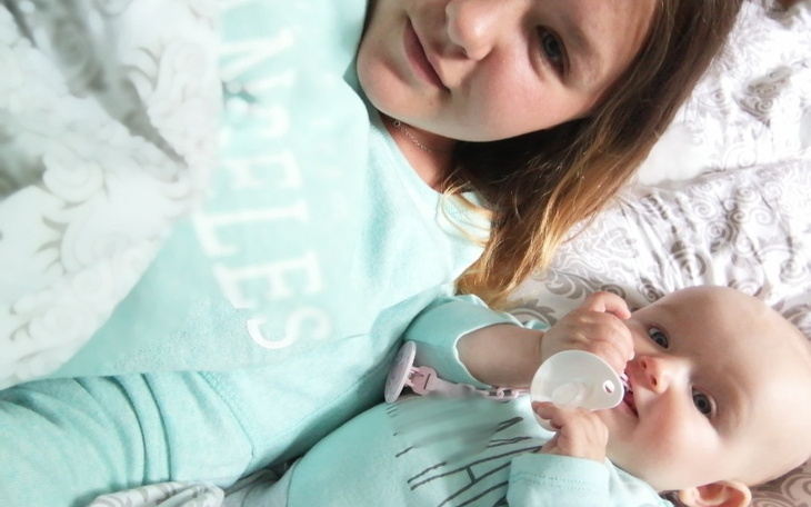 Mama z dzieckiem w łóżku, oboje w niebieskich piżamach.