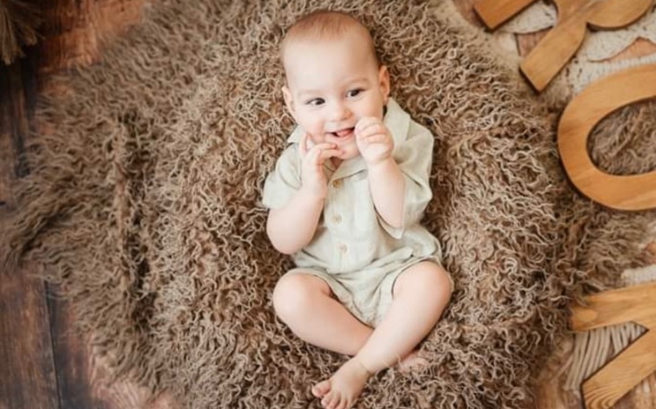 Małe dziecko uśmiechające się na miękkim dywanie.