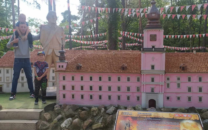 Rodzina i dzieci przy miniaturowym zamku w parku.