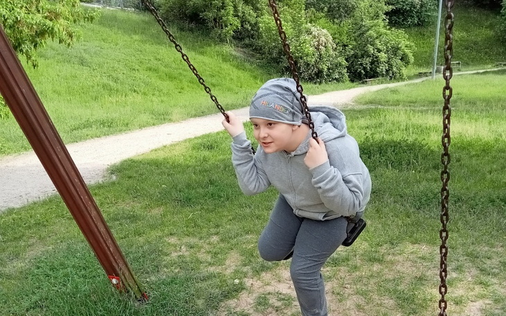 Chłopiec na huśtawce, uśmiechający się w parku.