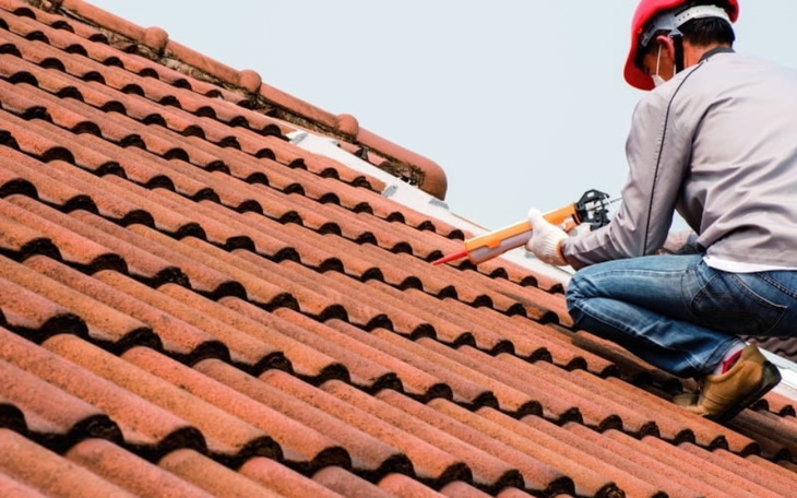 Mężczyzna naprawia dach, używając narzędzi.