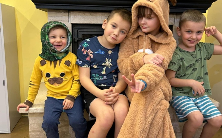 Czwórka dzieci w kolorowych ubraniach siedzi na kominku.