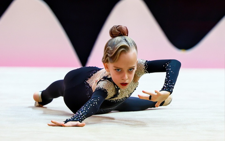 Młoda gimnastyczka w akcji, prezentująca skomplikowaną figurę.