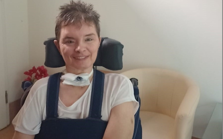 Kobieta na wózku inwalidzkim, uśmiechająca się do kamery.