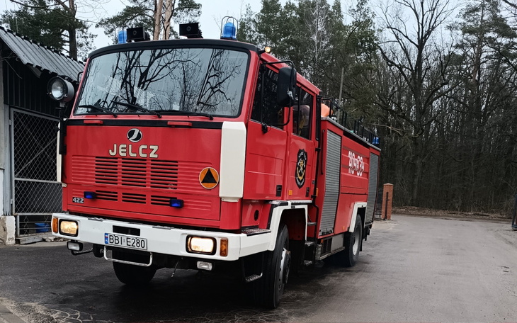 Czerwony wóz strażacki zaparkowany w lesie.