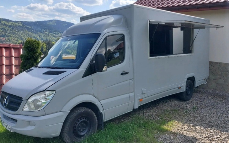 Samochód dostawczy zaparkowany obok budynku, gotowy do pracy.