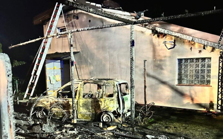 Zniszczony dom po pożarze, z uszkodzonym samochodem.