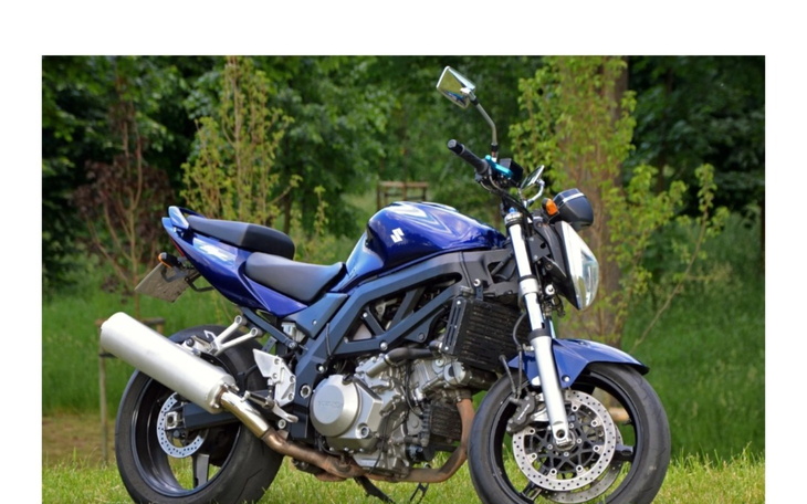 Niebieski motocykl na tle zielonej trawy.