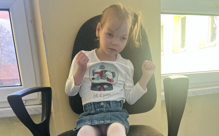 Dziewczynka siedząca na krześle, z zamyśloną miną.