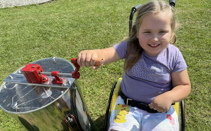 Dziewczynka na wózku inwalidzkim przy urządzeniu.