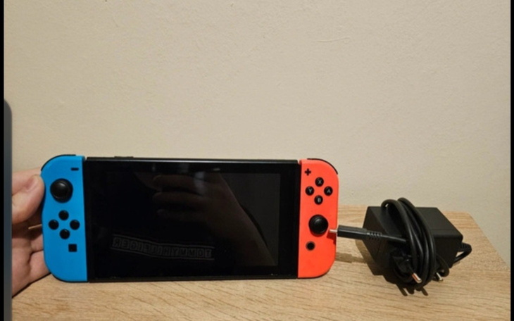 Konsola Nintendo Switch z kontrolerami na drewnianym stole.