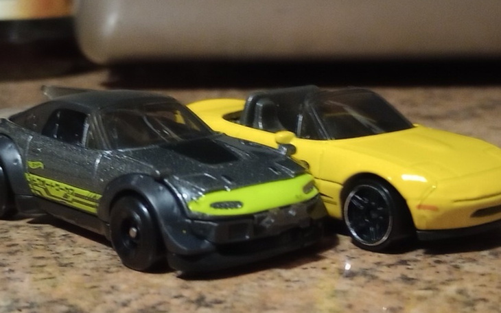 Dwa modele samochodów na stole, czarny i żółty.