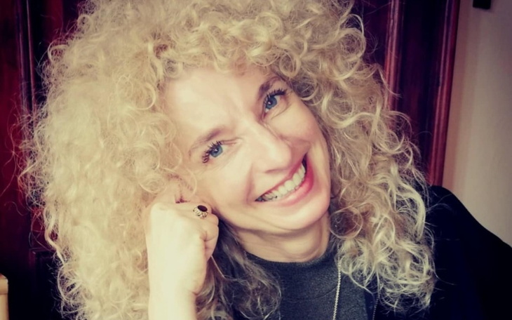 Uśmiechnięta kobieta z kręconymi włosami.