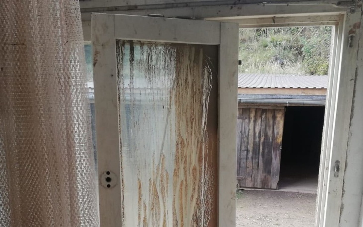 Otwarta drewniana drzwi z widokiem na zewnętrzny krajobraz.