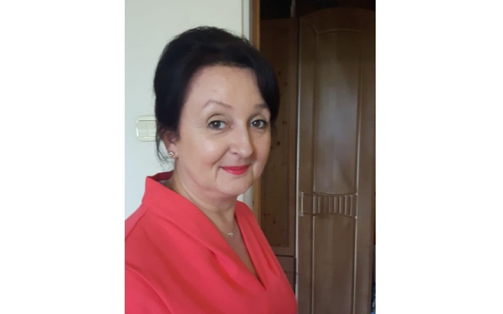 Kobieta w czerwonej bluzce, uśmiechająca się do kamery.