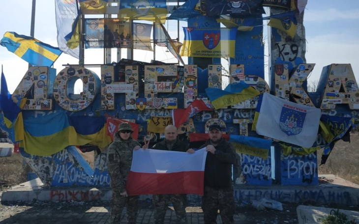 Grupa ludzi z flagami przed znakiem Doniecka.