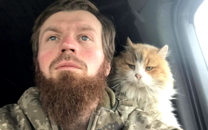 Mężczyzna z brodą i kotem siedzącym na jego ramieniu.