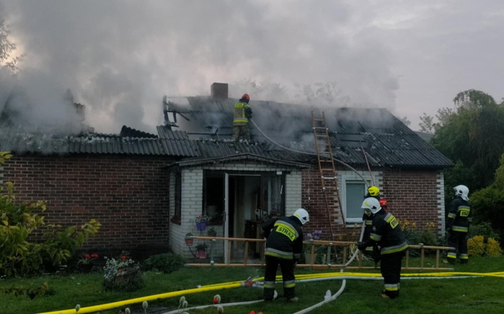 Strażacy gaszący pożar na dachu domu.