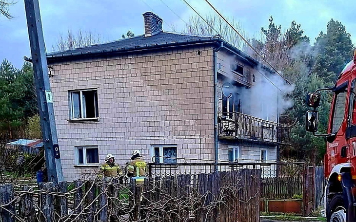 Dom z dymem wydobywającym się z okna, interwencja straży pożarnej.