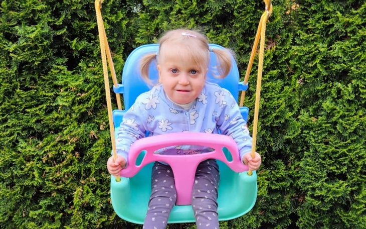 Mała dziewczynka bawi się na huśtawce w ogrodzie.