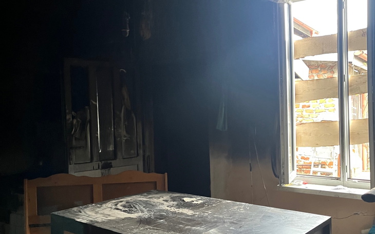 Ciemne wnętrze z popalonym stołem i oknem wpuszczającym światło.