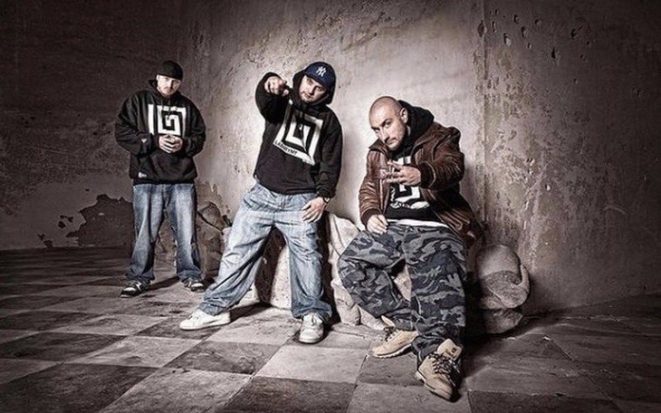 Trzech mężczyzn w hip-hopowych strojach w opuszczonym miejscu.
