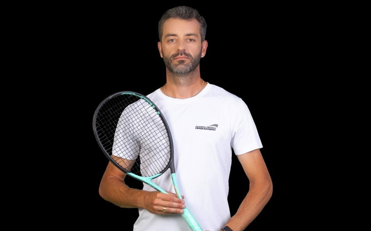 Mężczyzna trzyma rakietę tenisową, gotowy do gry.