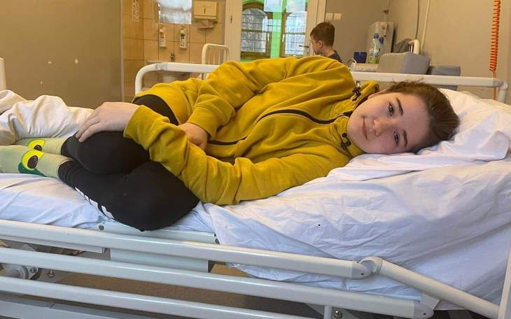 Młoda dziewczyna leży na łóżku w szpitalu, wygląda na zmęczoną.