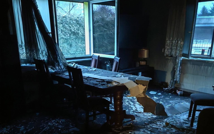 Zniszczony stół w ciemnym pomieszczeniu, z bałaganem.