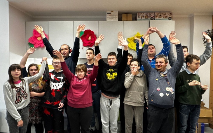 Grupa młodych ludzi z uniesionymi rękami, w radosnej atmosferze.