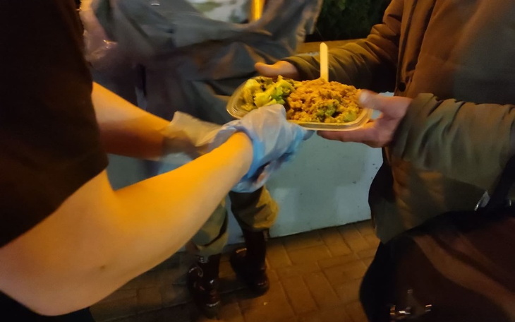 Osoba podająca jedzenie innym na ulicy.